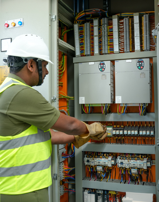 a man wearing a safety vest and gloves working in Hvac control cabinet