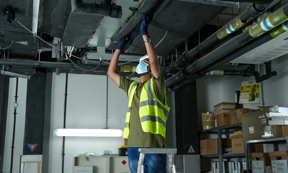 a man wearing a safety vest and gloves working on a metal structure hvac