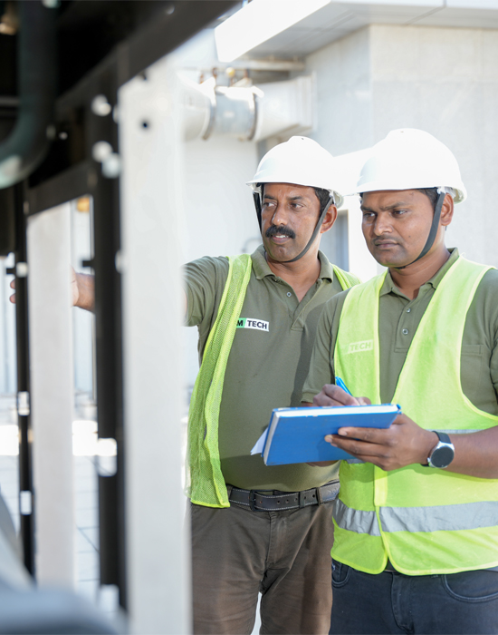 two man wearing a hard hat and holding a clipboard